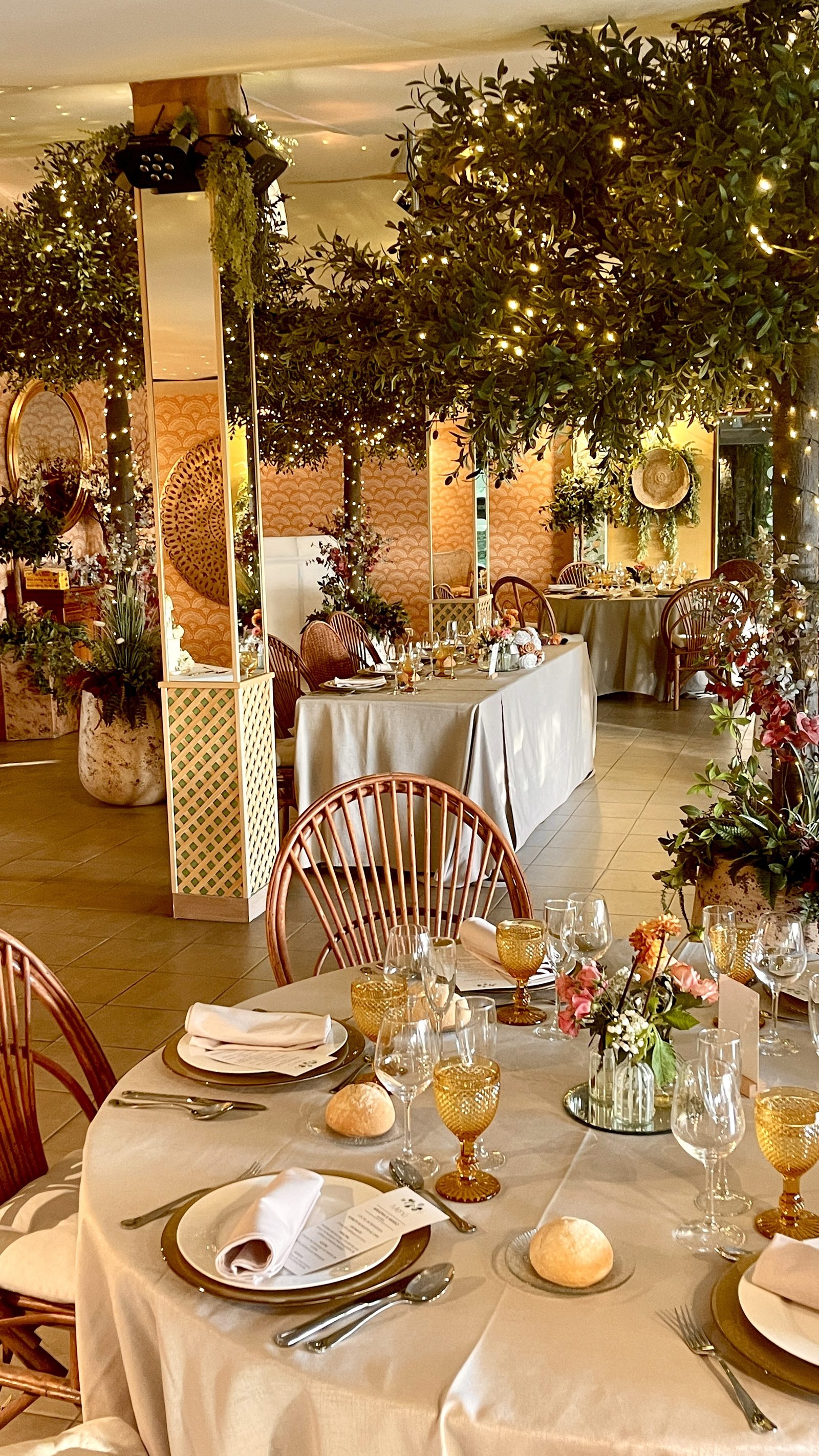 Banquete en un salón cubierto, entre árboles y luces