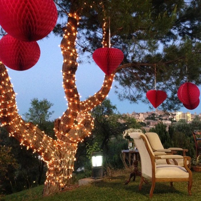 Árbol decorado con luces y farolillos rojos en el jardín al atardecer