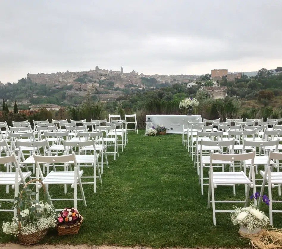 Ceremonia al aire libre con sillas blancas, decoración floral y vista panorámica