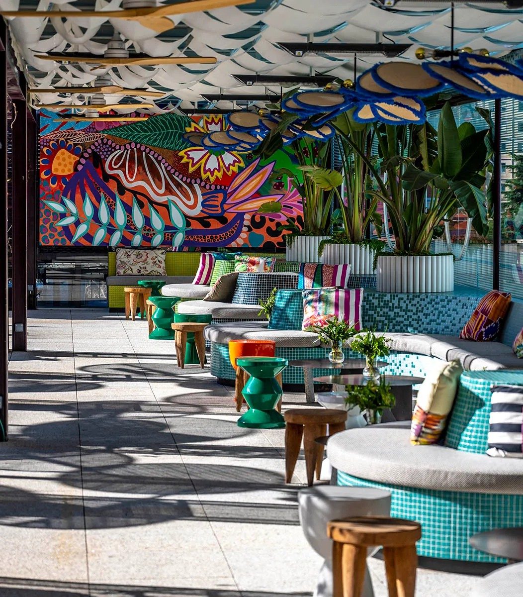 Espacio interior con mural, plantas y mobiliario moderno