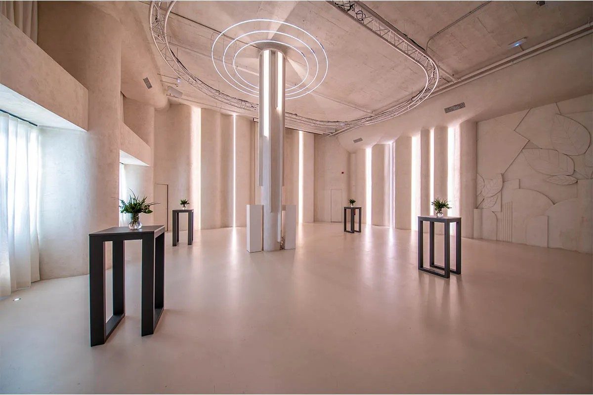 Sala blanca minimalista con iluminación moderna y mesas con flores