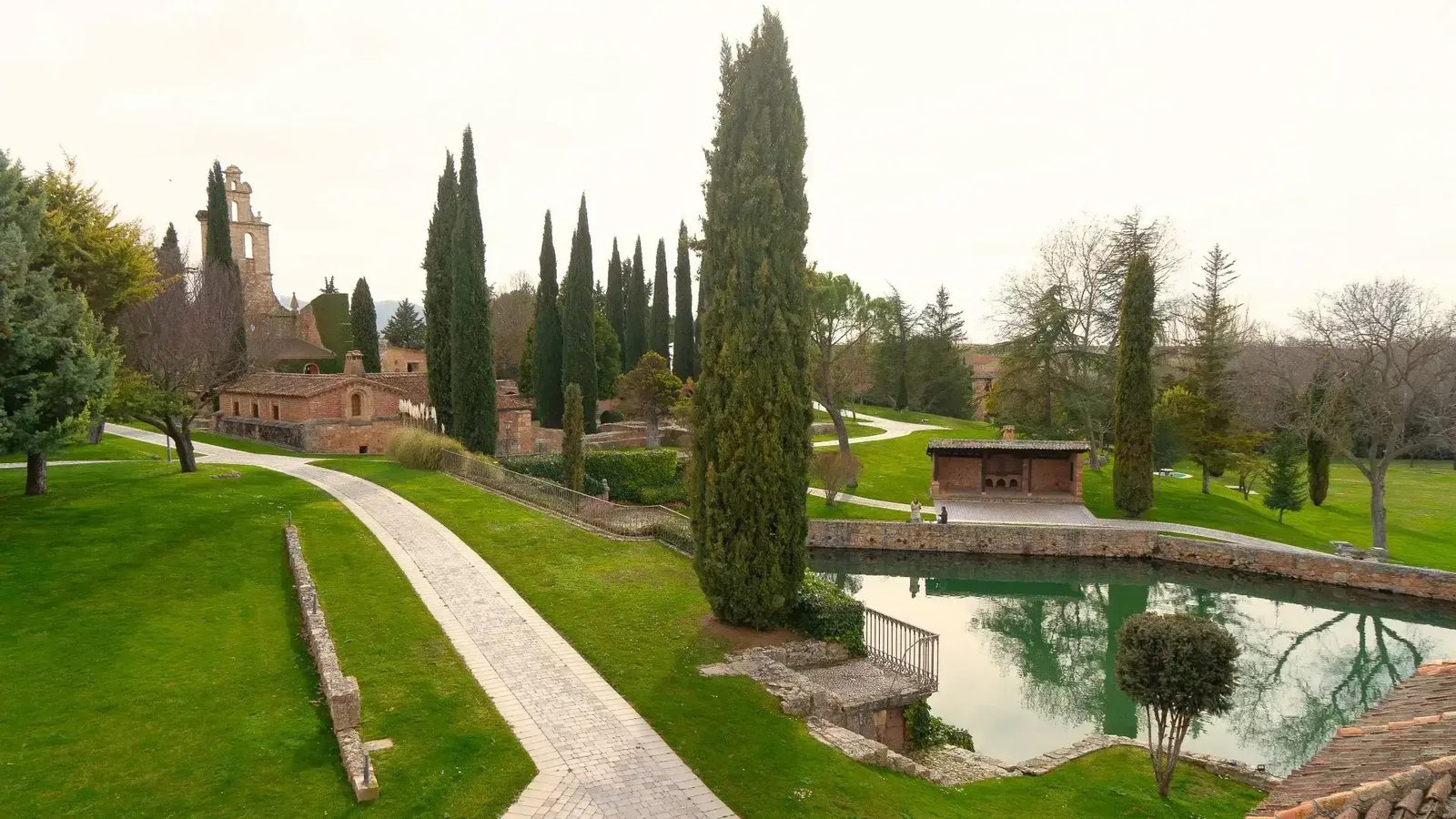 Jardín con sendero, cipreses y estanque