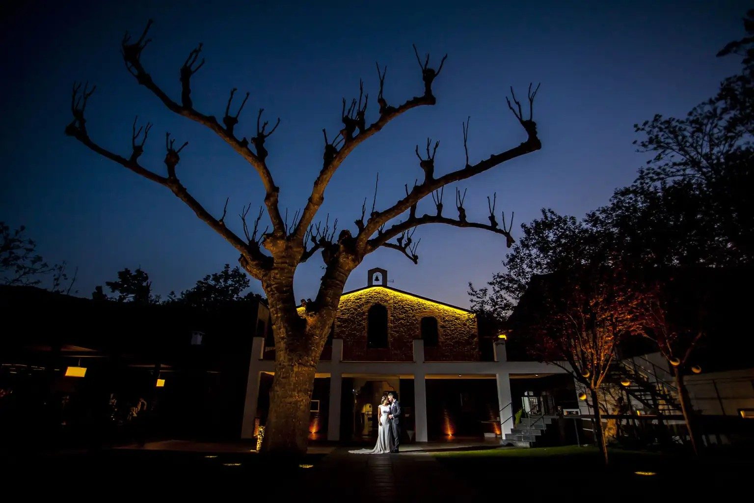 Edificio de la masía iluminado al anochecer con los novios