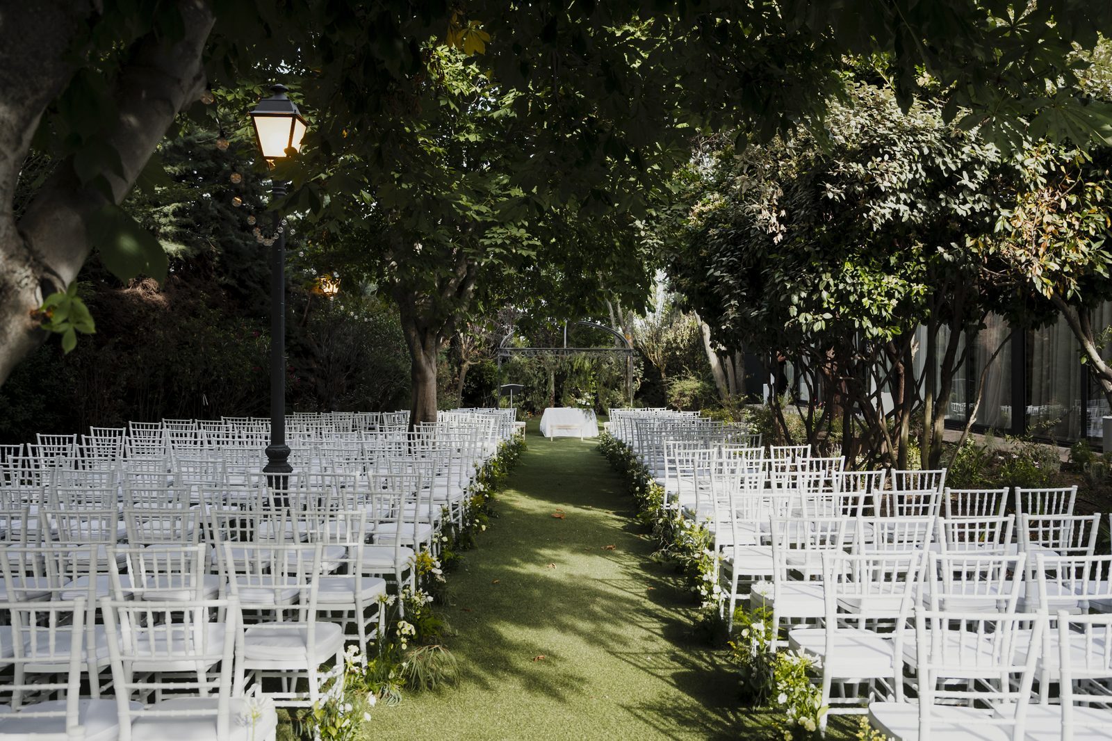 Ceremonia al aire libre en el pasillo del jardín, bajo los árboles.