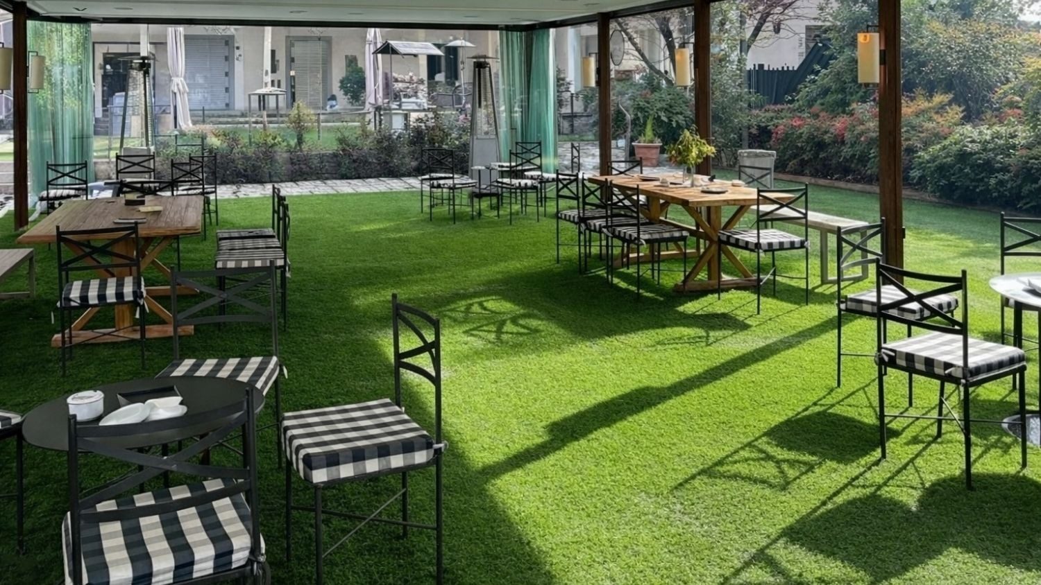 Zona acristalada de la Casa de las Flores con mesas metálicas y sillas negras