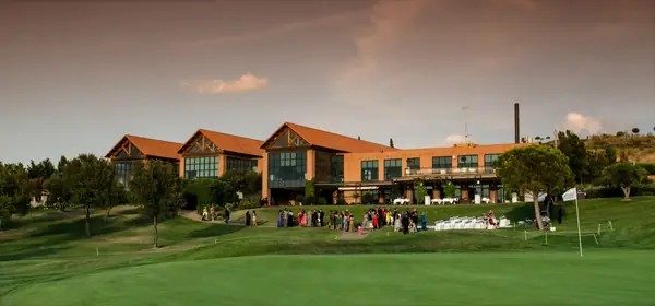 El club visto desde el campo de golf, con invitados en el césped