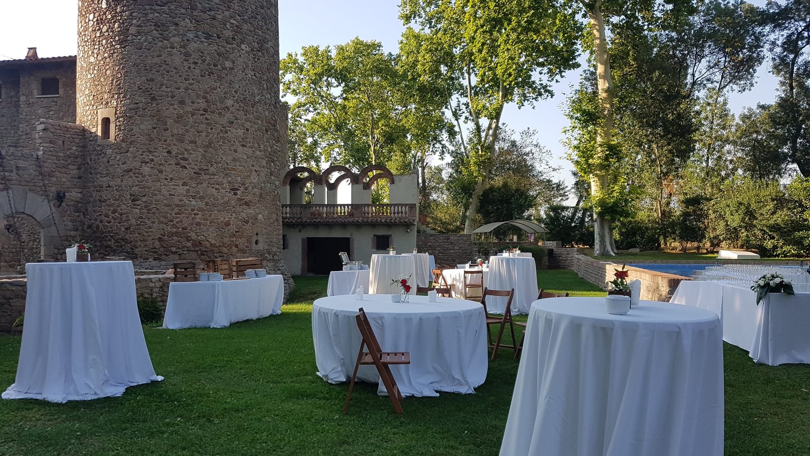 Montaje de aperitivo o cóctel de boda junto a la piscina, frente al torreón