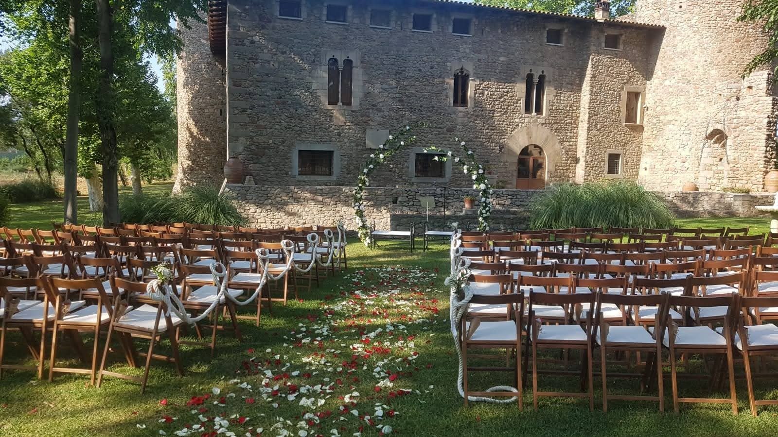 Montaje de ceremonia en el jardín, frente al castillo, con altar de semiarcos de flores y atril